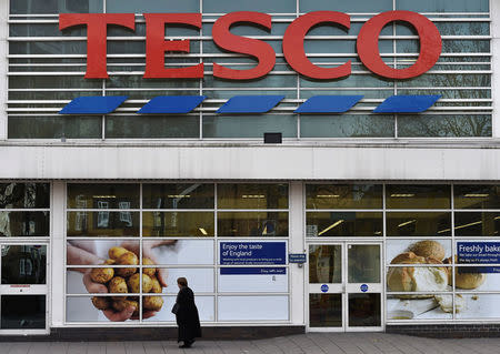 FILE PHOTO: A woman walks past a Tesco supermarket in central London, December 9, 2014. REUTERS/Toby Melville/File Photo