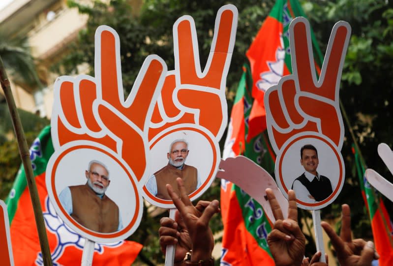 Supporters of BJP (Bharatiya Janata Party) gesture and hold placards after learning of initial poll results in Mumbai