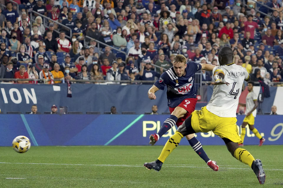 New England Revolution forward Adam Buksa (9) scores a goal ahead of Columbus Crew defender Jonathan Mensah (4) during the second half of a MLS soccer match, Saturday, Sept. 18, 2021, in Foxborough, Mass. (AP Photo/Mary Schwalm)