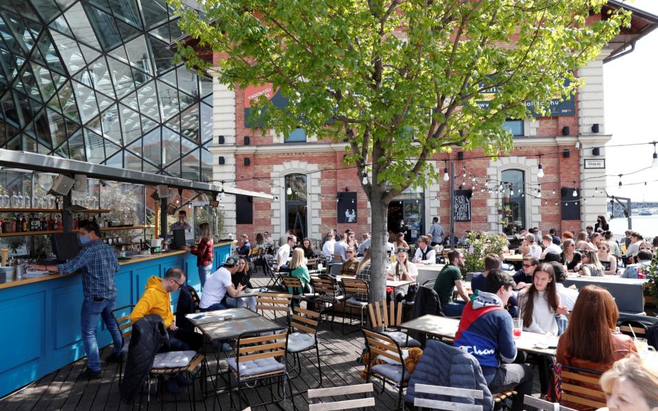 Customers enjoy the sunny weather as they sit outdoors after the Hungarian government reopened outdoor terraces in Budapest - Reuters