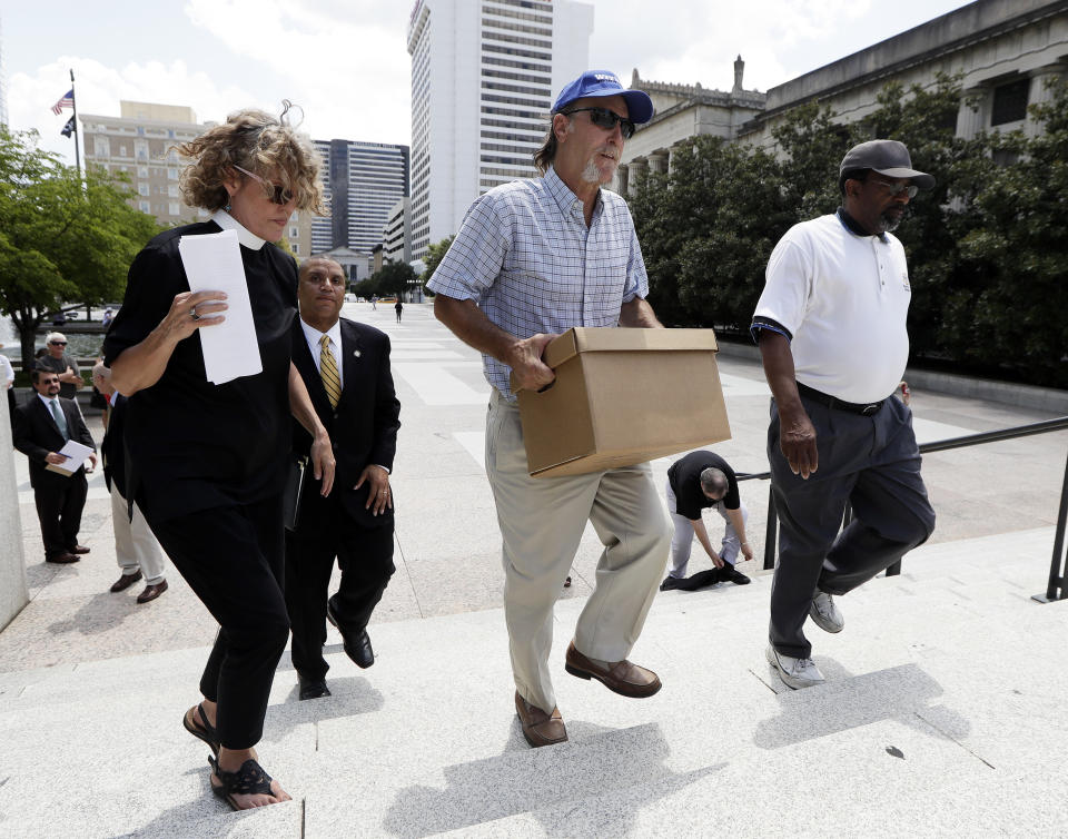 Ray Krone, center, who was the 100th inmate exonerated from death row since the death penalty was reinstated, carries a box of petition signatures to be delivered to Gov. Bill Haslam after a protest against the death penalty Tuesday, Aug. 7, 2018, in Nashville, Tenn. At left is Rev. Stacy Rector. Attorneys are asking the U.S. Supreme Court for a stay of execution for convicted child killer Billy Ray Irick after the Tennessee Supreme Court and governor decided against a delay. (AP Photo/Mark Humphrey)