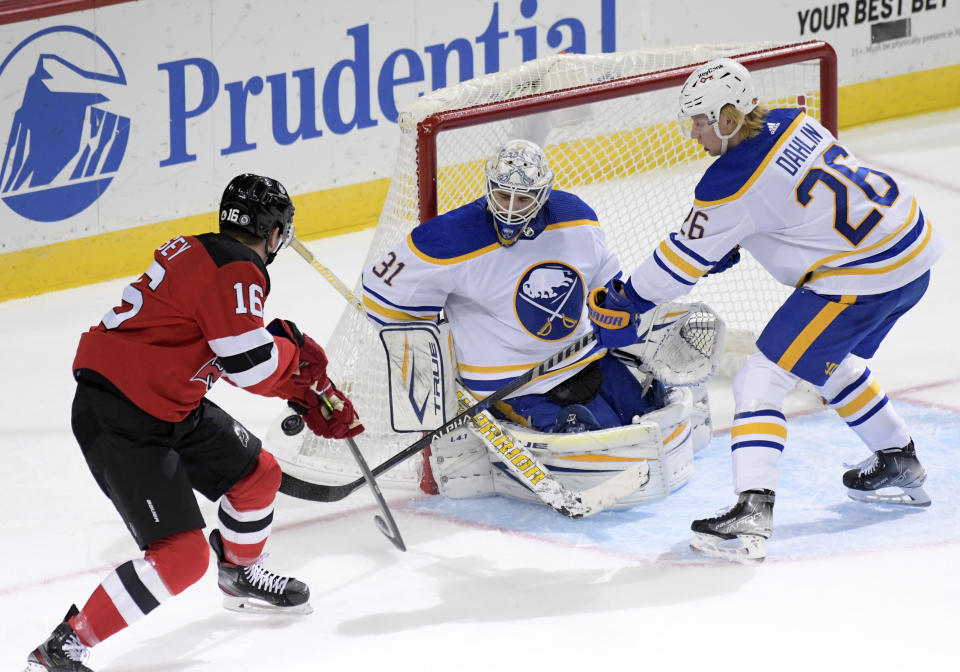 Buffalo Sabres goaltender Dustin Tokarski (31) deflects a shot by New Jersey Devils left wing Jimmy Vesey (16) as Sabres defenseman Rasmus Dahlin (26) helps on defense during the second period of an NHL hockey game Saturday, Oct. 23, 2021, in Newark, N.J. (AP Photo/Bill Kostroun)