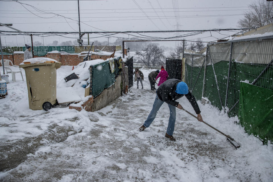 Unas personas palean la nieva en La Cañada Real Galiana, un enorme barrio pobre a las afueras de Madrid, España, considerado uno de los más grandes de Europa, el 8 de enero de 2021. (AP Foto/Manu Fernandez)