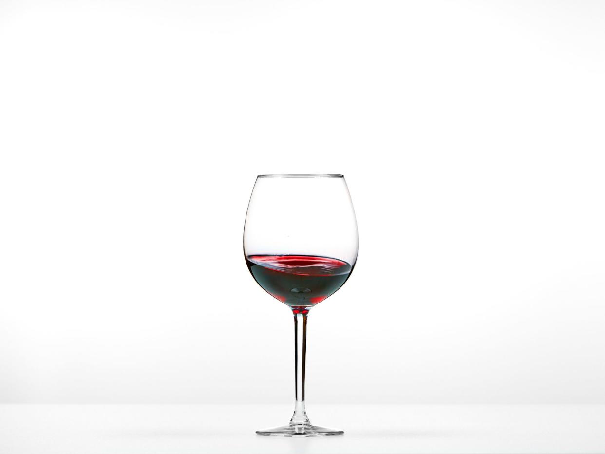 Red wine glass with wine in the center of pictures. The wine moves slightly up the glass.
