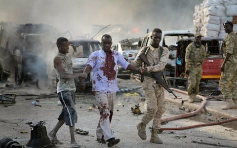 A Somali soldier helps a wounded civilian - Credit: AP Photo/Farah Abdi Warsameh