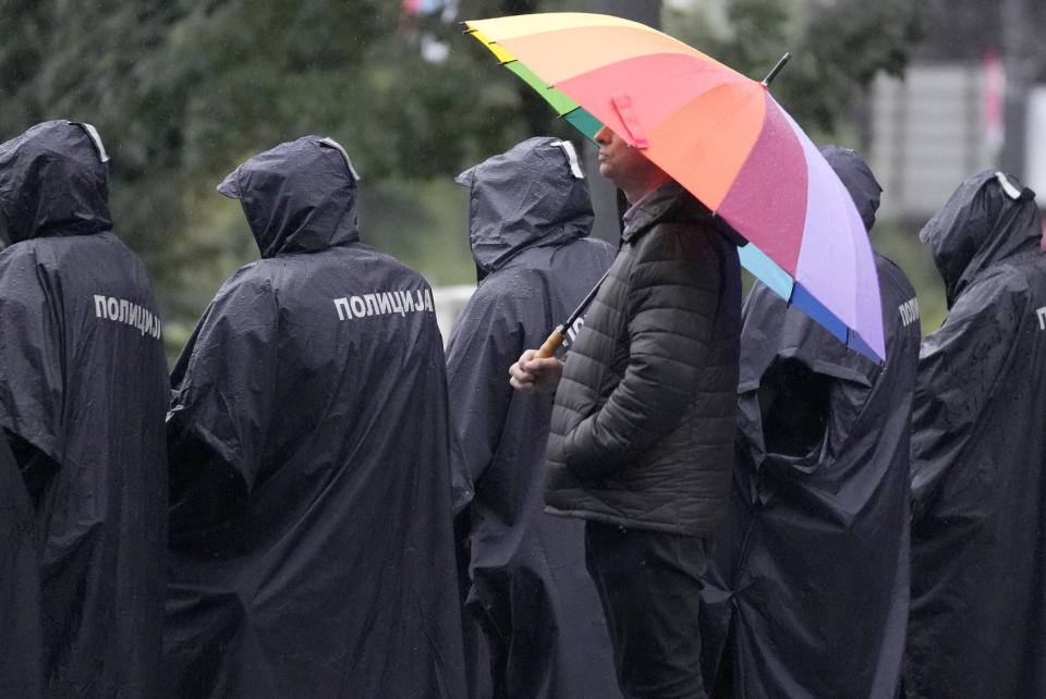 Pride event organizer Goran Miletic stands behind Serbian riot police officers during the European LGBTQ pride march in Belgrade, Serbia, Saturday, Sept. 17, 2022. Serbian police have banned Saturday's parade, citing a risk of clashes with far-right activists. (AP Photo/Darko Vojinovic)