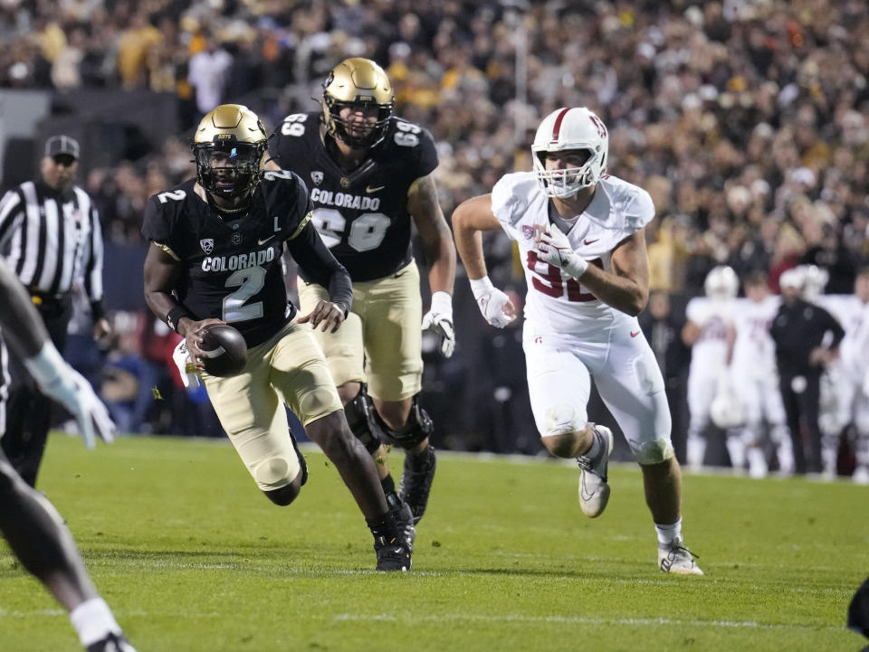 Colorado quarterback Shedeur Sanders (2) runs for a short gain as offensive tackle Gerad Christian-Lichtenhan and Stanford linebacker Lance Keneley follow deuring the first half of an NCAA college football game Friday, Oct. 13, 2023, in Boulder, Colo. (AP Photo/David Zalubowski)