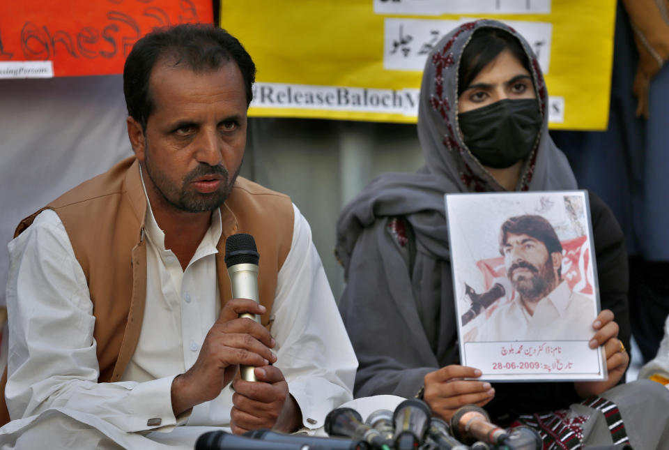 Nasrullah Baluch, left, leader of the Voice of Baluch Missing Persons, speaks while a woman holds portrait of her missing family members during a press conference in Islamabad, Pakistan, Saturday, Feb. 20, 2021. Dozens of relatives of Baluch missing persons, allegedly taken away by security agencies from restive Baluchistan province, Saturday ended their ten-day protest sleeping in the February cold near Pakistan parliament in capital Islamabad as minster for Human Rights assured their demand for recovery of loved ones would be taken seriously. (AP Photo/Anjum Naveed)