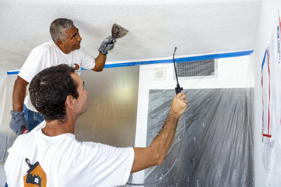 Workers stripping a popcorn ceiling