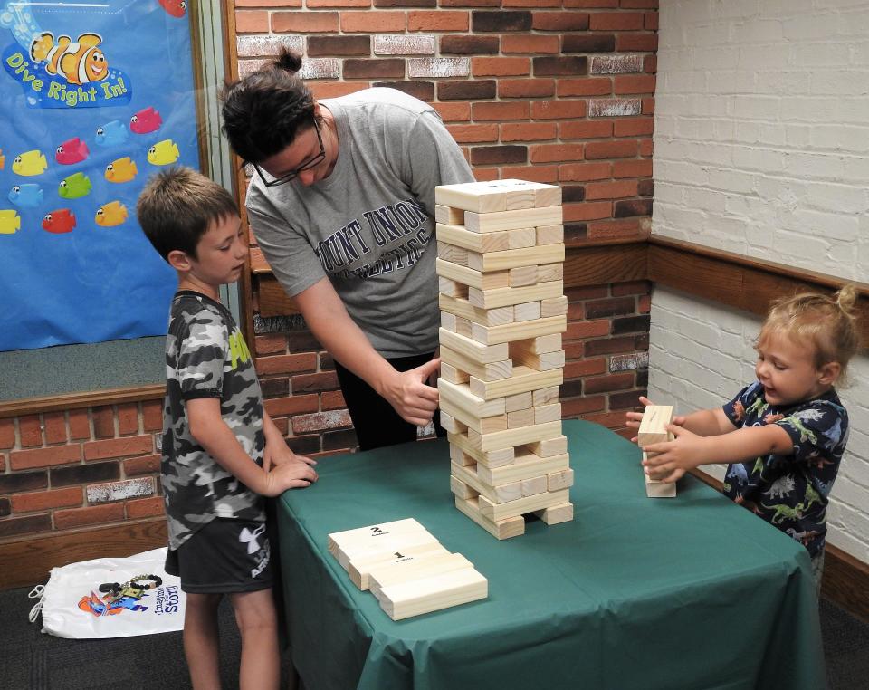 Jaron Hamilton, 7, Heather Wiggins and Atlas Wiggins, 2, play a game of large Jenga during a kick-off event for the summer reading program at the Coshocton Public Library last summer in this Tribune file photo. Giant Jenga games are one of the unique items people can check out from the library.