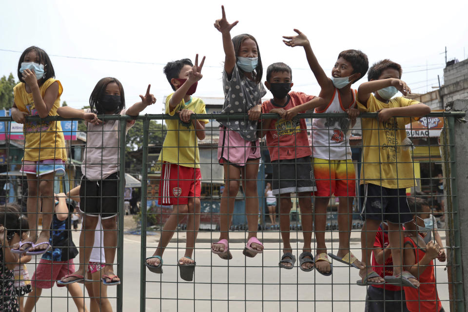 Children flash the "L" sign meaning "Fight!" during a motorcade before the burial of former Philippine President Benigno Aquino III in Quezon City, Philippines on Saturday, June 26, 2021. Aquino was buried in austere state rites during the pandemic Saturday with many remembering him for standing up to China over territorial disputes, striking a peace deal with Muslim guerrillas and defending democracy in a Southeast Asian nation where his parents helped topple a dictator. He was 61. (AP Photo/Basilio Sepe)