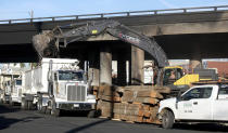 Crews continue to clear debris and shore up a stretch of Interstate 10, Tuesday morning Nov. 14, 2023, in Los Angeles. It will take at least three weeks to repair the Los Angeles freeway damaged in an arson fire, the California Gov. Gavin Newsom said Tuesday, leaving the city already accustomed to soul-crushing traffic without part of a vital artery that serves hundreds of thousands of people daily. (Dean Musgrove/The Orange County Register via AP)