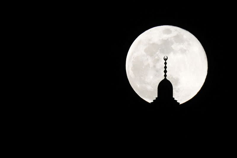 The full moon, also known as Supermoon or Flower Moon, rises over a mosque minaret on the 14th day of the holy fasting month of Ramadan, in Amman