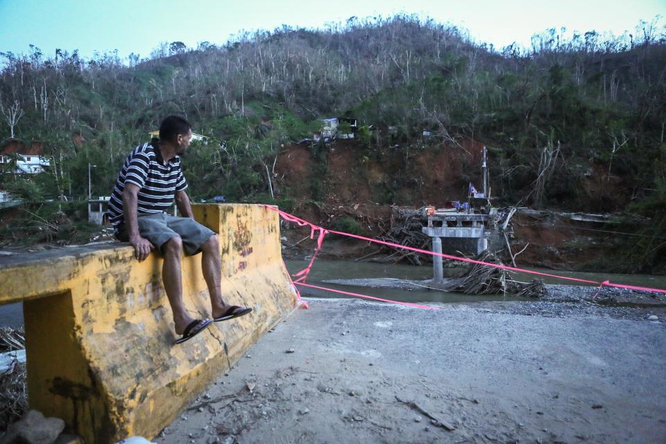 A man sits on the edge of a broken bridge spanning the Vivi River on Oct. 20, 2017 in Utuado, Puerto Rico. (Photo: Mario Tama via Getty Images)
