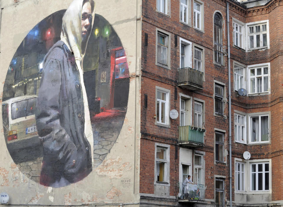 <p>A woman hangs laundry on a balcony next to a new mural by Spanish painter Sebas Velasco, created on a blank wall of an old house in the district of Praga, in Warsaw, Poland, Oct. 1, 2016. (Photo: Alik Keplicz/AP)</p>