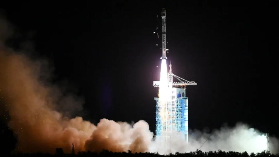 a rocket launches at night next to a blue launch tower