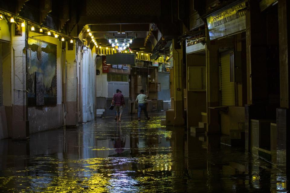 People walk through a submerged street after heavy rain in Muscat, Oman