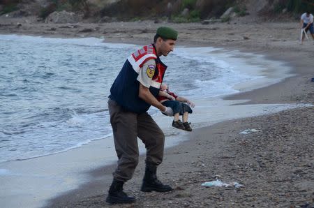 A Turkish gendarmerie carries a young migrant, who drowned in a failed attempt to sail to the Greek island of Kos, in the coastal town of Bodrum, Turkey, September 2, 2015. REUTERS/Nilufer Demir/DHA