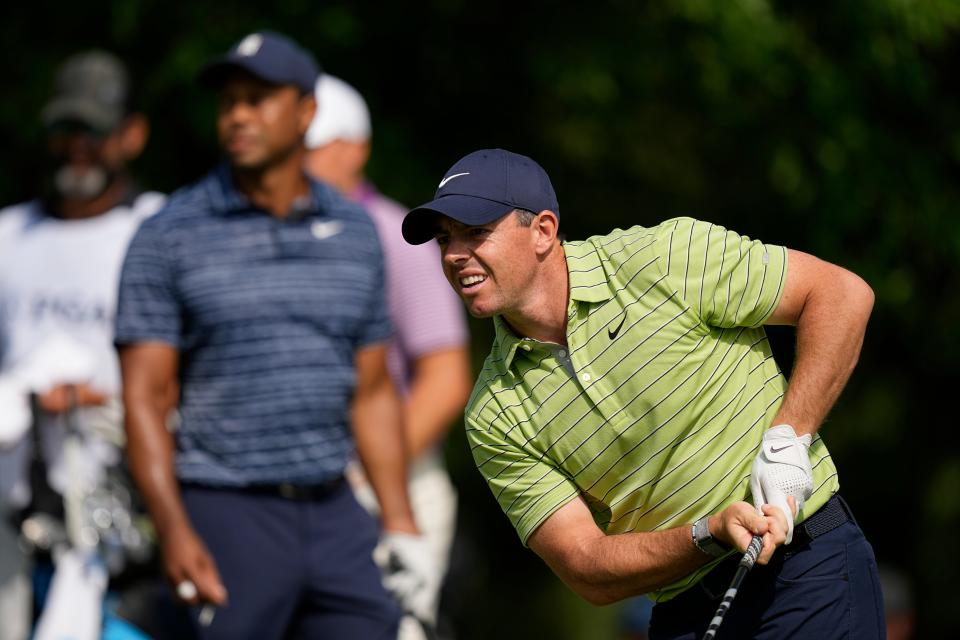 Rory McIlroy watches his tee shot on the 17th hole as Tiger Woods looks on during Thursday's first round of the PGA Championship.
