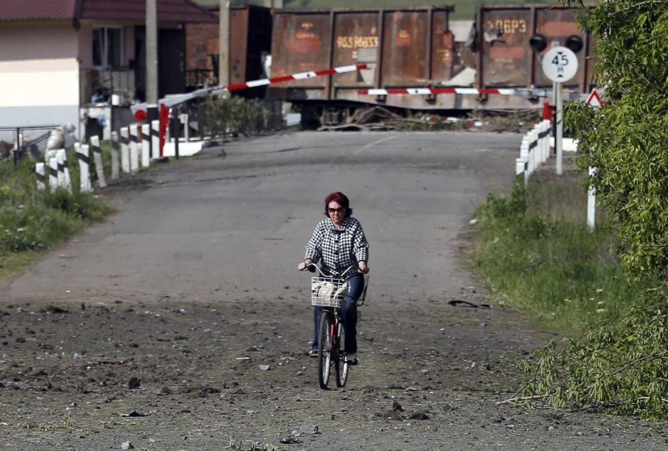 A woman rides a bicycle in front of destroyed barricades on a road leading into Slovyansk, eastern Ukraine, Tuesday, May 13, 2014. Residents of two restive regions in eastern Ukraine engulfed by a pro-Russian insurgency are casting ballots in contentious and hastily organized independence referenda. Sunday's ballots seek approval for declaring so-called sovereign people's republics in the Donetsk and Luhansk regions, where rebels have seized government buildings and clashed with police and Ukrainian troops. (AP Photo/Darko Vojinovic)