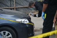 EDITORS NOTE: Graphic content / Members of Police Crime Scene Unit investigate around a car used by alleged gunmen at the main entrance of the Pakistan Stock Exchange building in Karachi on June 29, 2020. - At least six people were killed when gunmen attacked the Pakistan Stock Exchange in Karachi on June 29, with a policeman among the dead after the assailants opened fire and hurled a grenade at the trading floor, police said. (Photo by Rizwan TABASSUM / AFP) (Photo by RIZWAN TABASSUM/AFP via Getty Images)