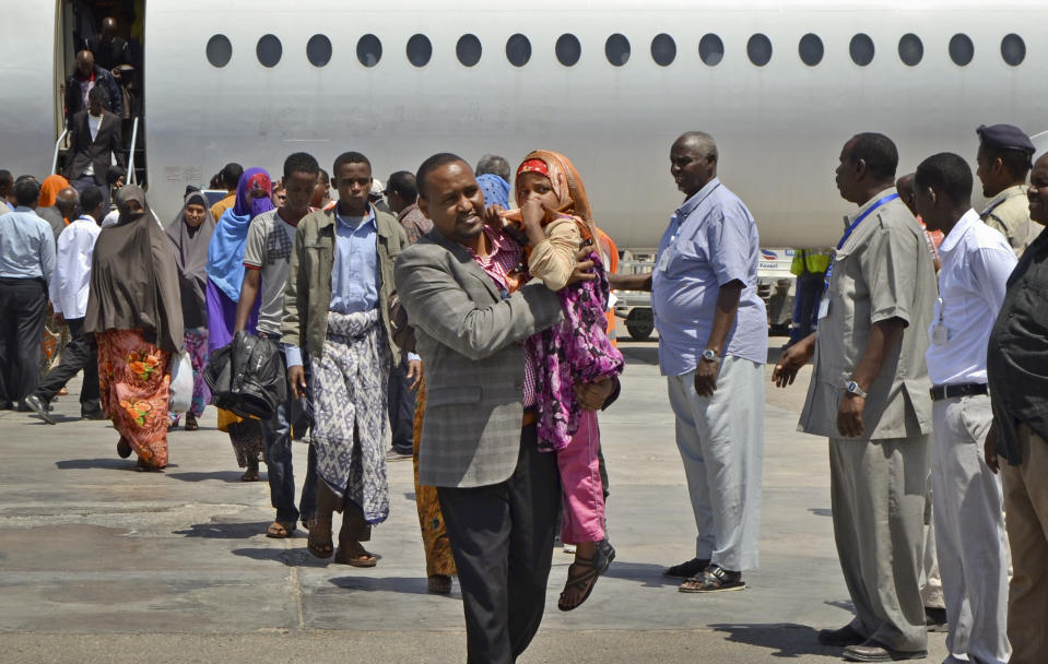 Somali Member of Parliament Muse Sheikh Omar, center, carries a young Somali girl deportee as he helps Somalis who had been deported from Kenya to Somalia from their aircraft after it landed at the airport in Mogadishu, Somalia, Wednesday, April 9, 2014. Kenya's security minister said Wednesday that 82 Somali nationals have been deported in an ongoing security crackdown following recent terror attacks in Kenya's capital and the port city of Mombasa. (AP Photo/Farah Abdi Warsameh)