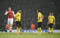 Arsenal's Per Mertesacker (L) gives a thumbs-up as Borussia Dortmund players stand dejected after a goal was scored during their Champions League group D soccer match in London November 26, 2014. REUTERS/Dylan Martinez