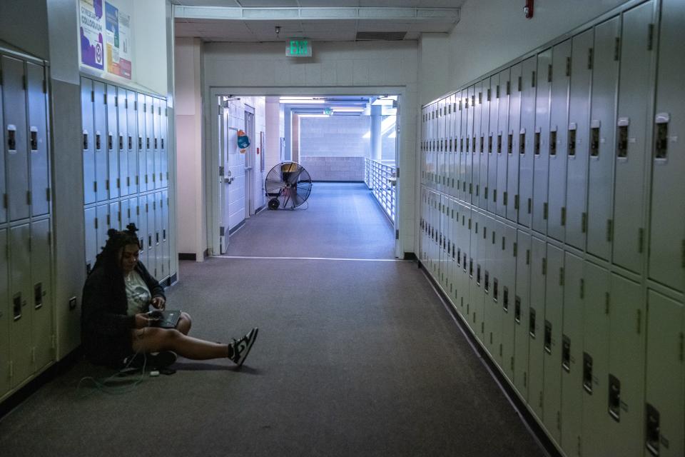 Fort Collins High School senior Janaya Bottoms-Garcia studies near a large fan placed in a second-floor hallway Tuesday in Fort Collins. Because the school does not have a working air conditioning system, fans are used in classrooms and hallways to circulate air on hot days.