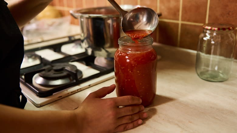 ladling tomato sauce in jar