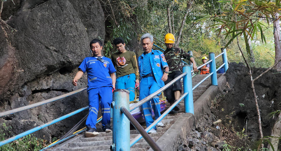 Emergency workers carry My Alchin's body down the steep steps in a body bag.