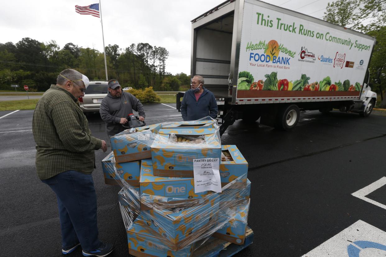 David Cryer, left, of the Hands Across Middlesex Food Pantry, an interfaith organization of local churches, checks food as it is delivered at their food pantry on Monday, April 27, 2020, in Locust Hill, Va.