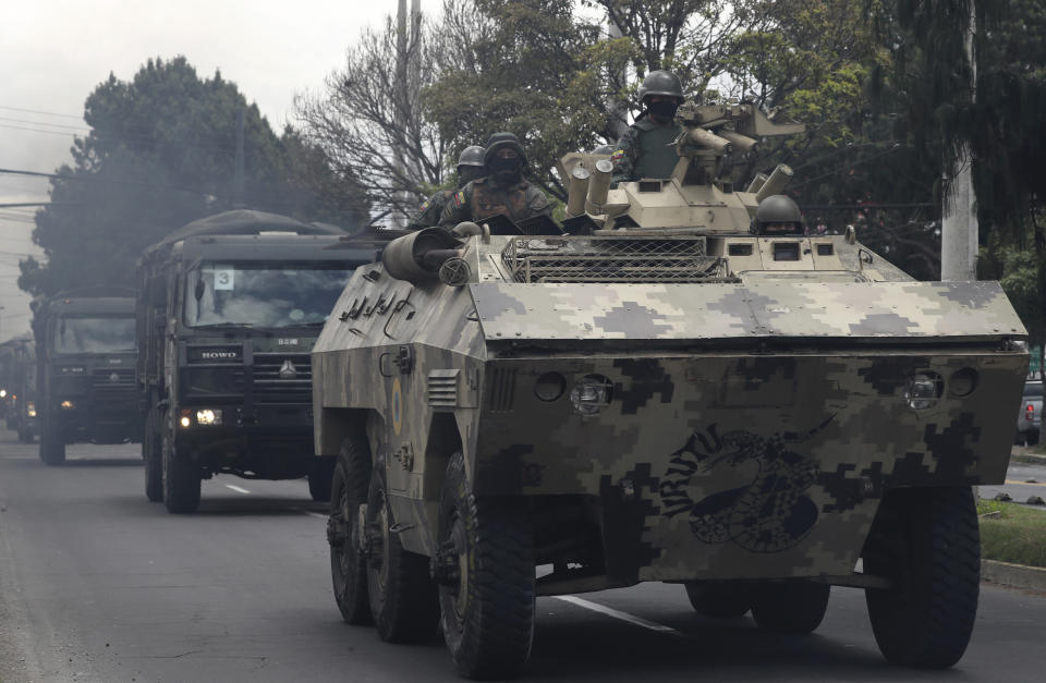 Soldiers in an armored vehicle patrol in a fast-moving convoy during a 24-hour military curfew after violent protests across Quito, Ecuador, Sunday, Oct. 13, 2019. The government and indigenous protesters planned to begin negotiations aimed at defusing more than a week of demonstrations against a plan to remove fuel subsidies as part of an International Monetary Fund austerity package. (AP Photo/Dolores Ochoa)