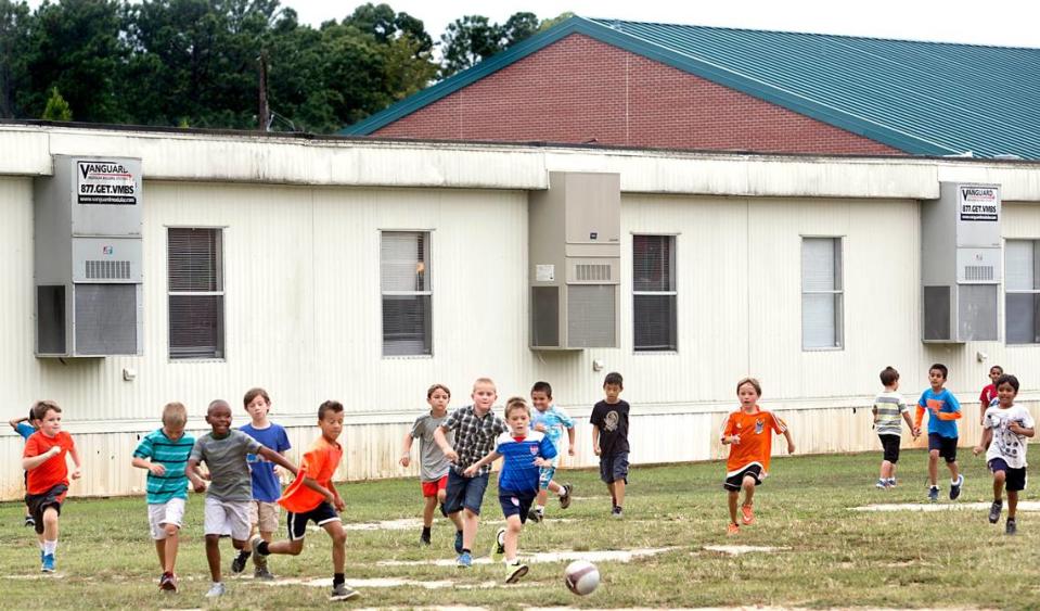 Second-graders at Highcroft Drive Elementary School in Cary play together on a grassy field next to a modular unit behind the school in this 2015 file photo.