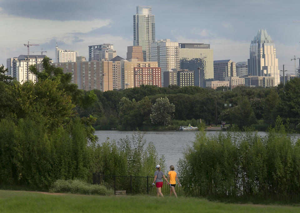 FILE - In this Aug. 31, 2016, file photo, women walk against the Austin skyline in Austin, Texas. From the middle of the Obama administration to the midpoint of the Trump administration, household income grow the most in growing tech and entertainment centers like in Austin, Nashville, Pittsburgh and large chunks of the West Coast, while it declined the most in former manufacturing and mining hubs like High Point, North Carolina and Scranton, Pa., according to new figures released Thursday, Dec. 19, 2019, by the U.S. Census Bureau. (Ralph Barrera/Austin American-Statesman via AP, File)