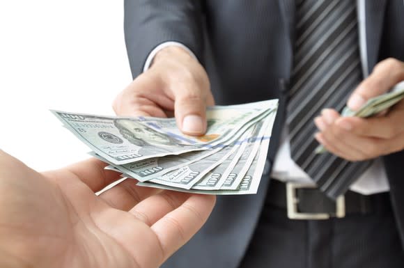 Businessman handing over $100 bills