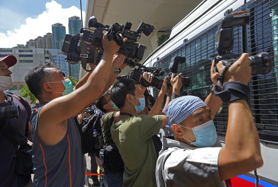A police van is surrounded by photographers as a 23-year-old man, Tong Ying-kit, arrives at a court in Hong Kong Monday, July 6, 2020. Tong has become the first person in Hong Kong to be charged under the new national security law, for allegedly driving a motorcycle into a group of policemen while bearing a flag with the "Liberate Hong Kong, revolution of our time" slogan. (AP Photo/Vincent Yu)