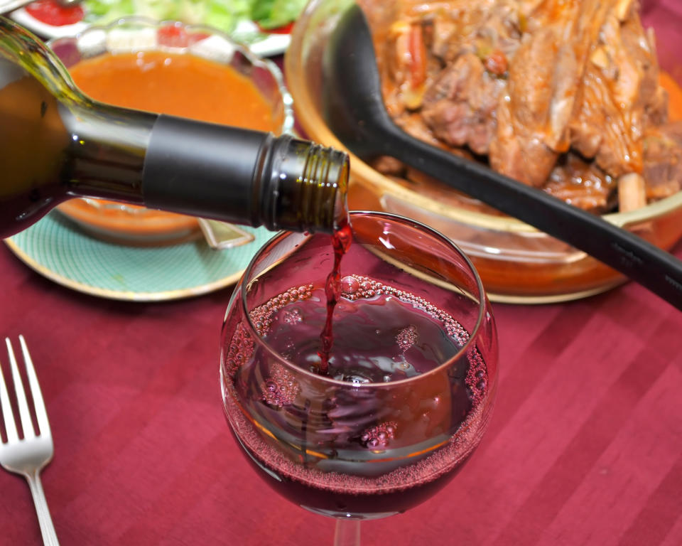 TORONTO, ONTARIO, CANADA - 2010/12/26: Close up of red wine pouring into a wine glass. Different food is on the table in the blurred background. (Photo by Roberto Machado Noa/LightRocket via Getty Images)