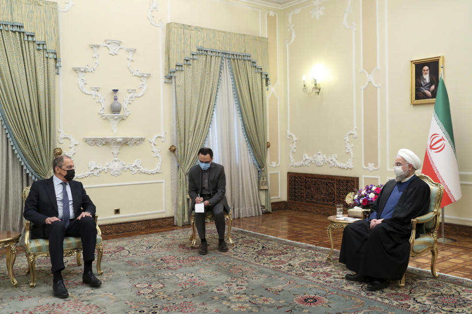 In this photo released by the official website of the office of the Iranian Presidency, Iranian President Hassan Rouhani, right, and Russian Foreign Minister Sergey Lavrov, left, wear face masks to curb the spread of COVID-19 during their talks in Tehran, Iran, Tuesday, April 13, 2021. (Iranian Presidency Office via AP)