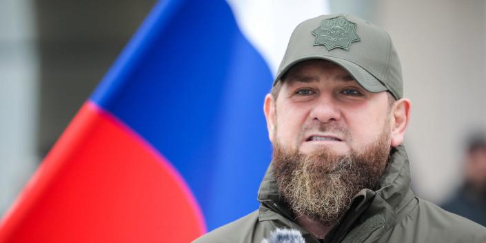 Chechen leader Ramzan Kadyrov at a microphone in front of a Russian flag.