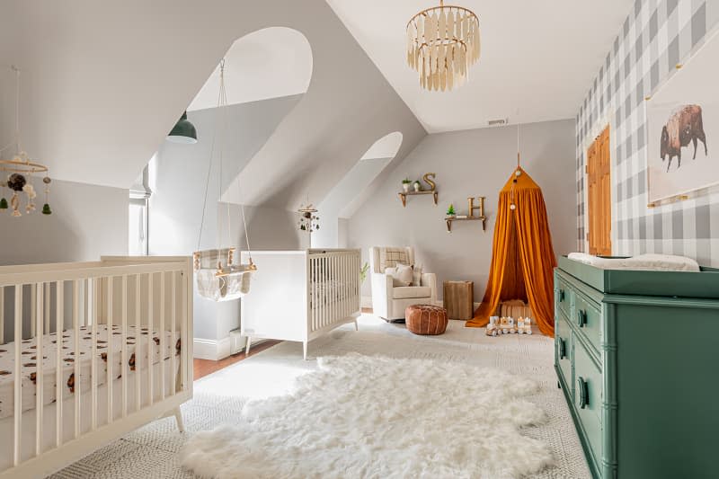 nursery with 2 cribs, gray walls and one gray and white gingham wall, and orange and green accents