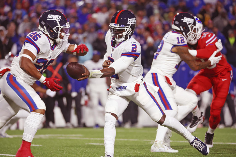 New York Giants quarterback Tyrod Taylor, center, hands off to running back Saquon Barkley (26) during the first half of an NFL football game against the Buffalo Bills in Orchard Park, N.Y., Sunday Oct. 15, 2023. (AP Photo/ Jeffrey T. Barnes)