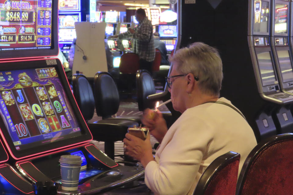 A gambler lights a cigarette while playing a slot machine at Harrah's casino in Atlantic City, N.J., Sept. 29, 2023. On Monday, Jan. 29, 2024, a New Jersey Senate committee advanced a bill that would end smoking at Atlantic City's nine casinos. (AP Photo/Wayne Parry)