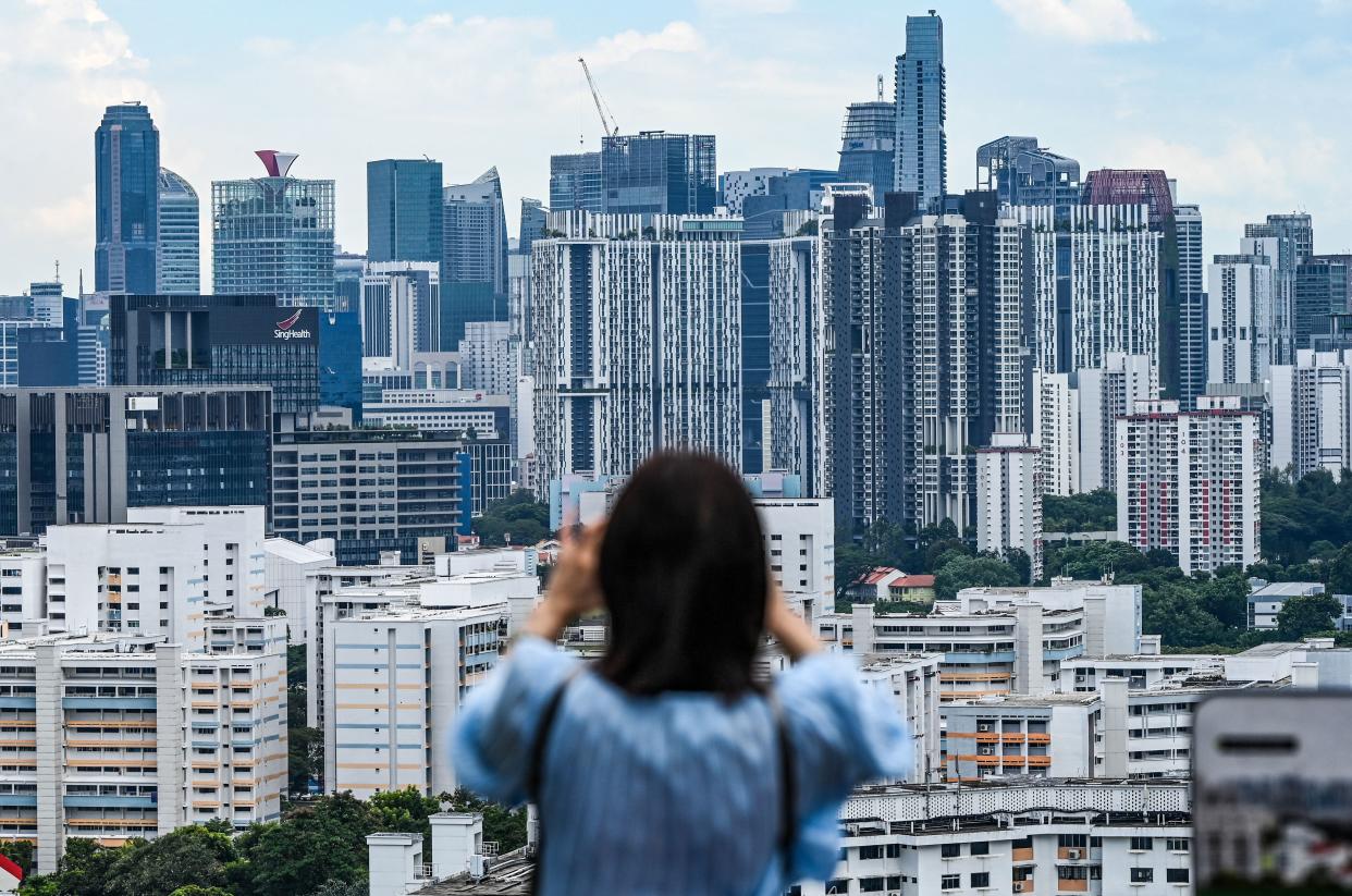 A woman takes pictures of the Singapore skyline of buildings from Mount Faber. 