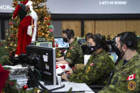 In this photo provided by the North American Aerospace Defense Command, 22 Wing members are seen showing how they track Santa on his sleigh on Christmas eve during a media preview at the Canadian Forces Base in North Bay on Dec. 9, 2021. In a Christmas Eve tradition going on its 66th year, a wildly popular program run by the U.S. and Canadian militaries is providing real-time updates on Santa's progress around the globe -- and fielding calls from children who want to know St. Nick's exact whereabouts. (Sable Brown/NORAD via AP)
