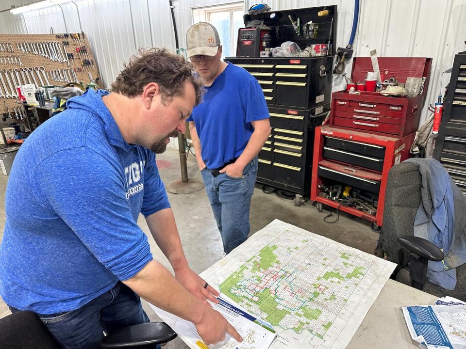 Scott Heeg looks over a county map and diagram of a proposed irrigation project in Acadia Valley while his brother Steve Heeg looks on. 