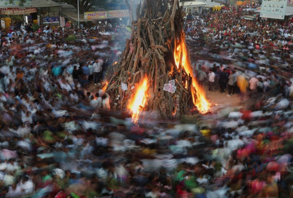 Hindu devotees walk around a bonfire during a ritual known as “Holika Dahan” which is part of the Holi festival celebrations on the outskirts of Ahmedabad (REUTERS)