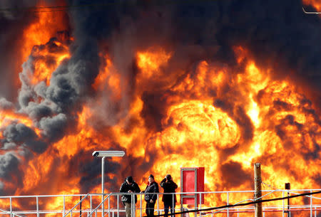 People stand opposite a blaze that erupted in a fuel tank at Oil Refineries Ltd in the Israeli northern city of Haifa December 25, 2016. REUTERS/Baz Ratner