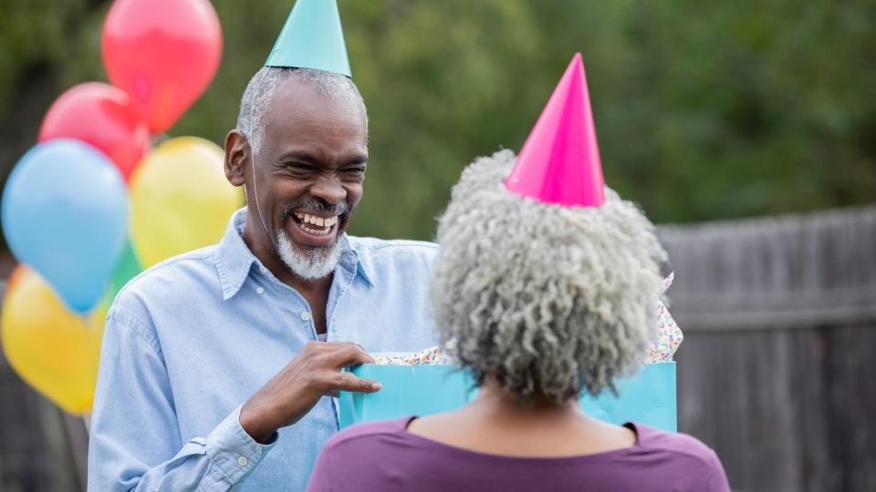 senior couple celebrate birthday with balloons, party hats, and gifts