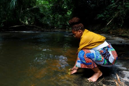 A member of a heritage tour group says a prayer to her enslaved ancestors at the Assin Manso river