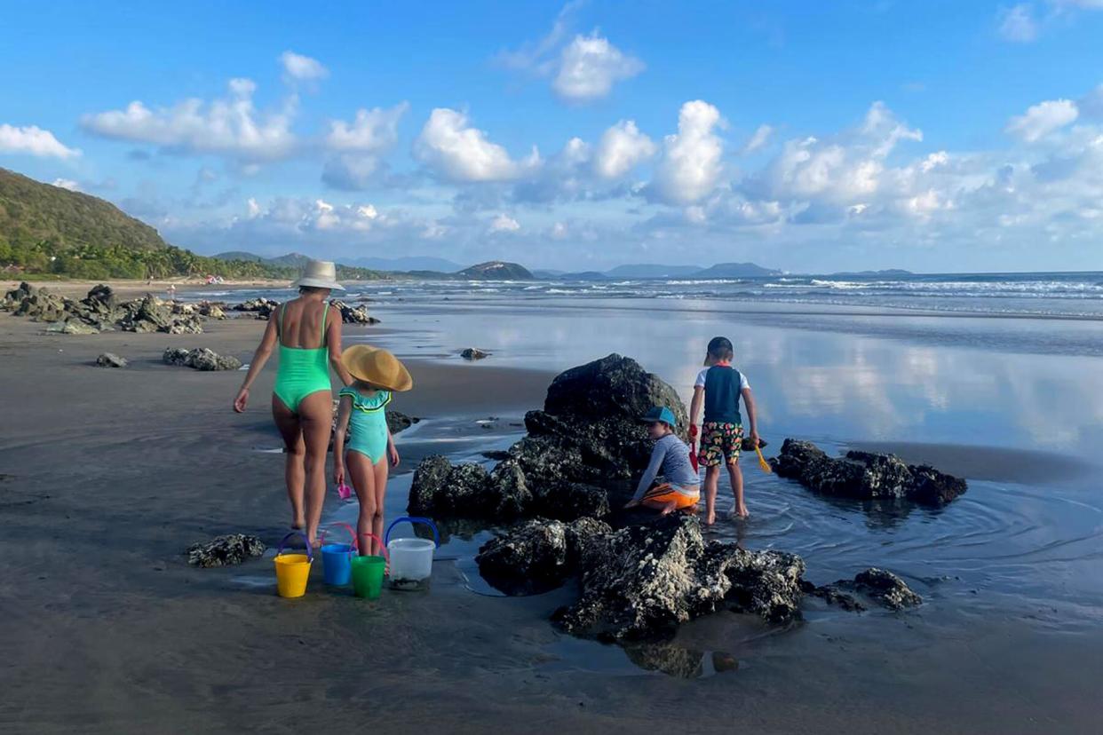 Family looking in the tide pools along the beach in Zihuatanejo, Mexico